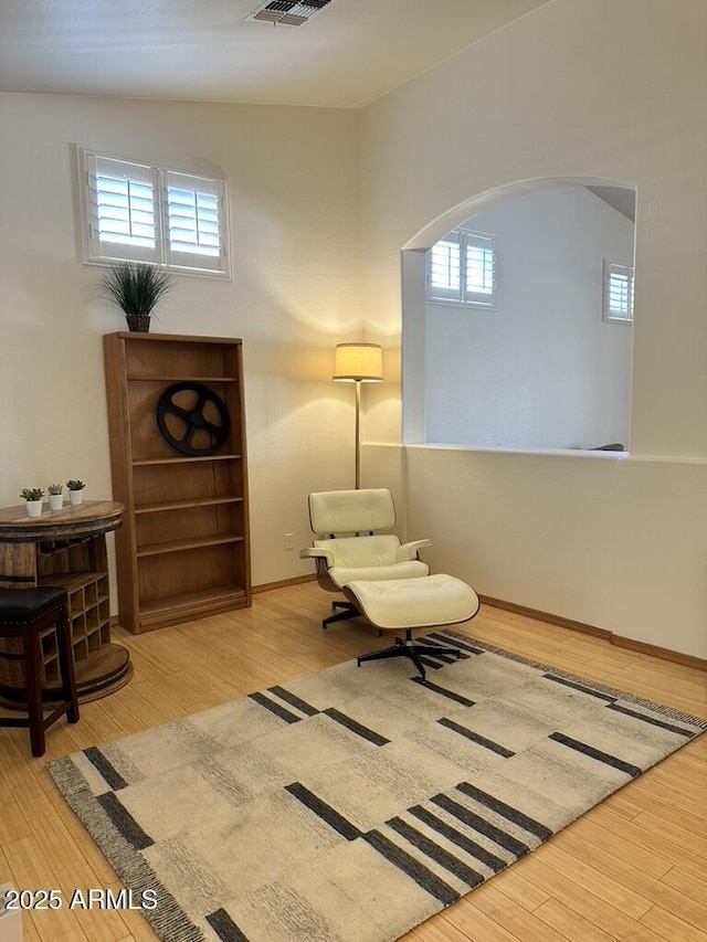 sitting room featuring arched walkways, wood finished floors, and plenty of natural light