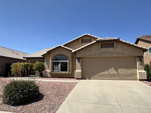 view of front of property featuring stucco siding, driveway, an attached garage, and a tiled roof