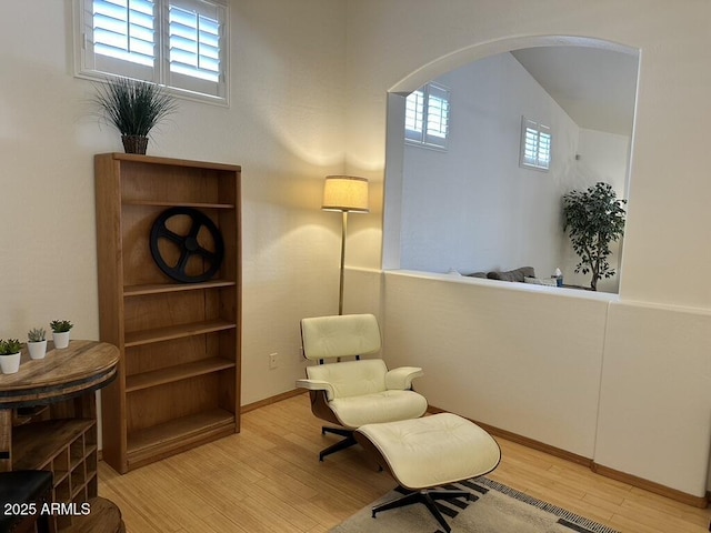living area with arched walkways, wood finished floors, and baseboards