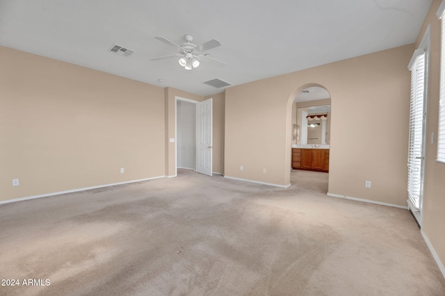 unfurnished bedroom with connected bathroom, light colored carpet, and ceiling fan