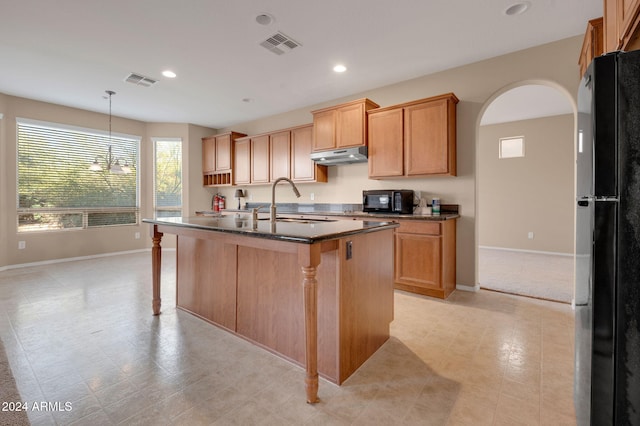 kitchen with sink, a center island with sink, a kitchen breakfast bar, pendant lighting, and black appliances