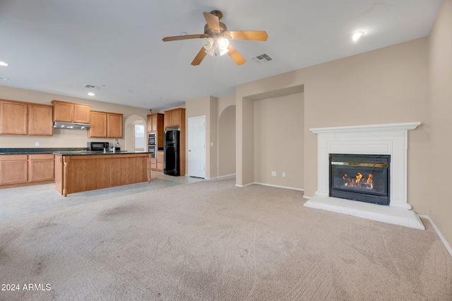 kitchen with sink, light colored carpet, a kitchen island, ceiling fan, and black appliances