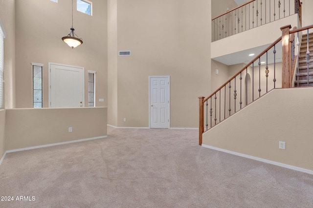 carpeted foyer entrance featuring a towering ceiling