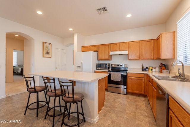 170 E Canary Ct, San Tan Valley, AZ 85143 - kitchen featuring appliances with stainless steel finishes, under cabinet range hood, a sink, arched walkways, and a breakfast bar