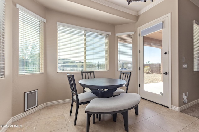 dining area featuring light tile patterned floors, crown molding, and baseboards