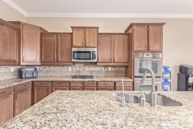 kitchen featuring a sink, ornamental molding, backsplash, and stainless steel appliances