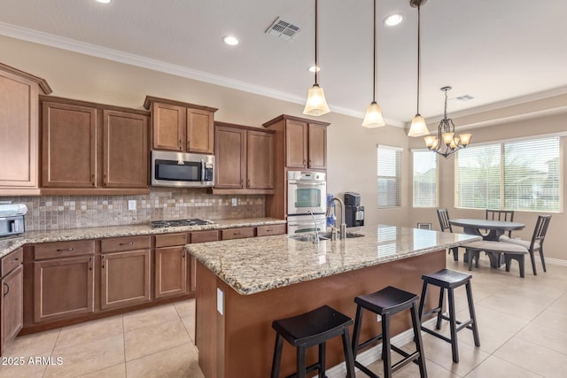 kitchen featuring decorative backsplash, crown molding, appliances with stainless steel finishes, and a sink