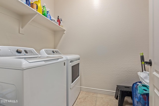 laundry room featuring light tile patterned floors, baseboards, laundry area, and washing machine and clothes dryer