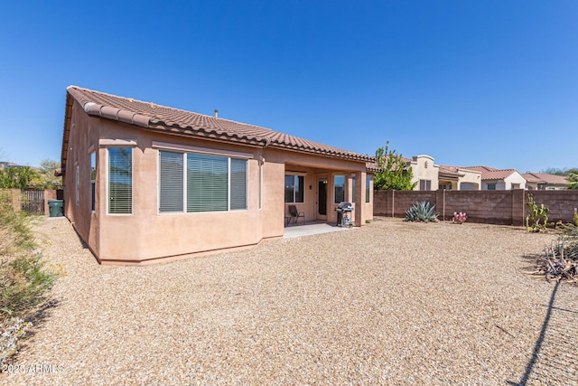 back of property with a patio area, stucco siding, a tile roof, and a fenced backyard