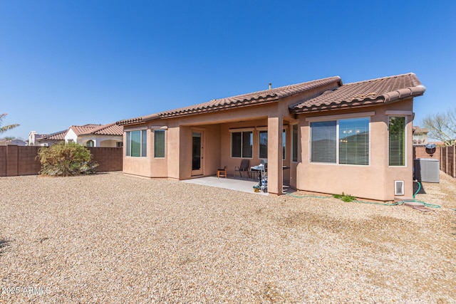 rear view of house featuring cooling unit, a fenced backyard, stucco siding, a tile roof, and a patio area