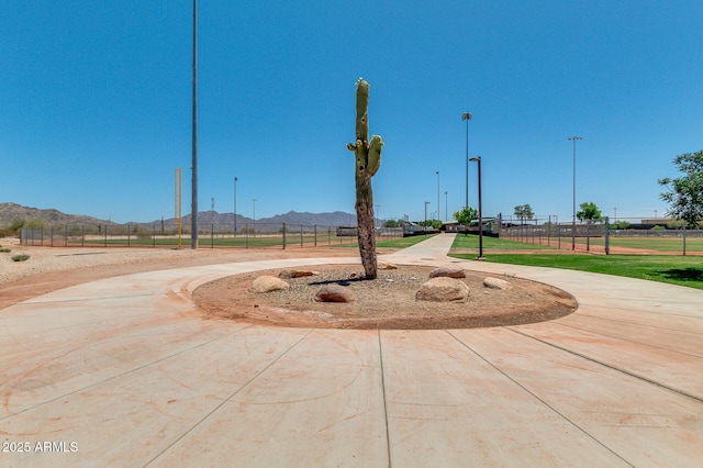 view of property's community with a mountain view, curved driveway, and fence