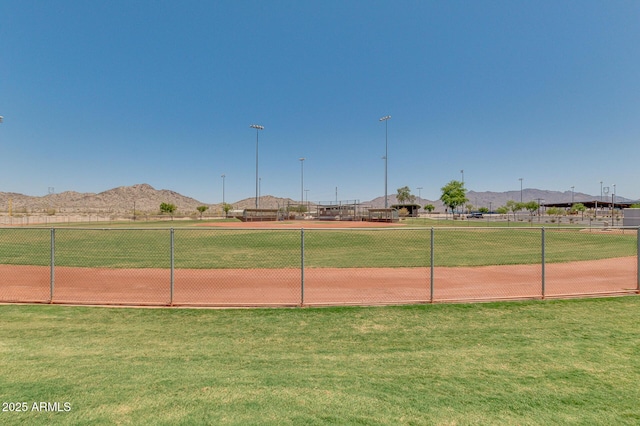 surrounding community with a lawn, a mountain view, and fence