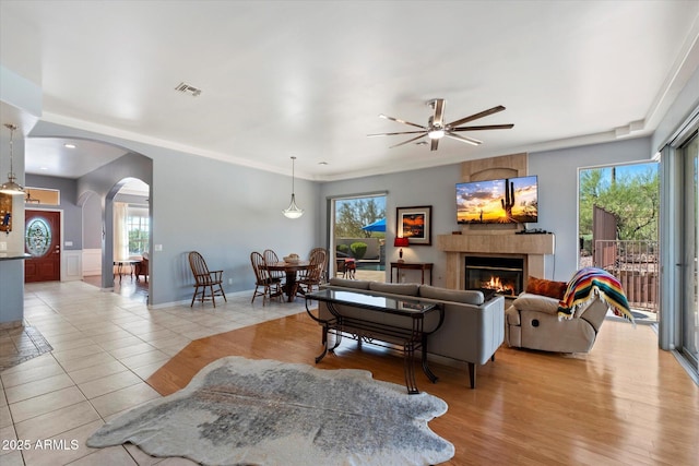 34611 N Sunset Trl, Cave Creek, AZ 85331 - living room featuring arched walkways, ceiling fan, a lit fireplace, and healthy amount of natural light