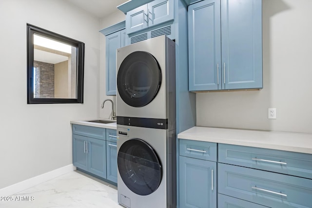 washroom featuring stacked washer and dryer, sink, and cabinets