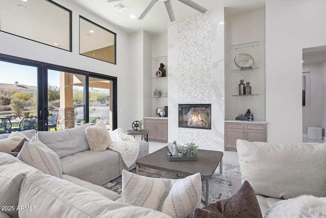 living room featuring a towering ceiling, a premium fireplace, and built in features