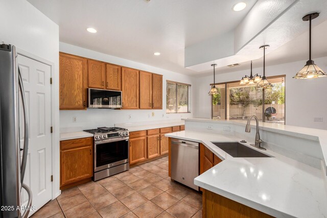 13599 W Monte Vista Rd, Goodyear, AZ 85395 - kitchen with appliances with stainless steel finishes, a sink, light countertops, brown cabinetry, and decorative light fixtures