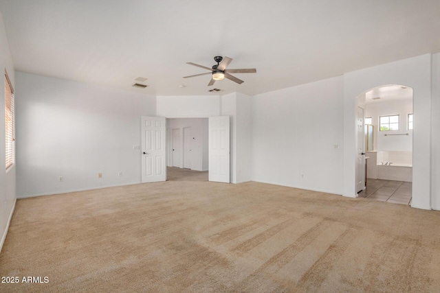 13599 W Monte Vista Rd, Goodyear, AZ 85395 - empty room with arched walkways, ceiling fan, light colored carpet, and baseboards