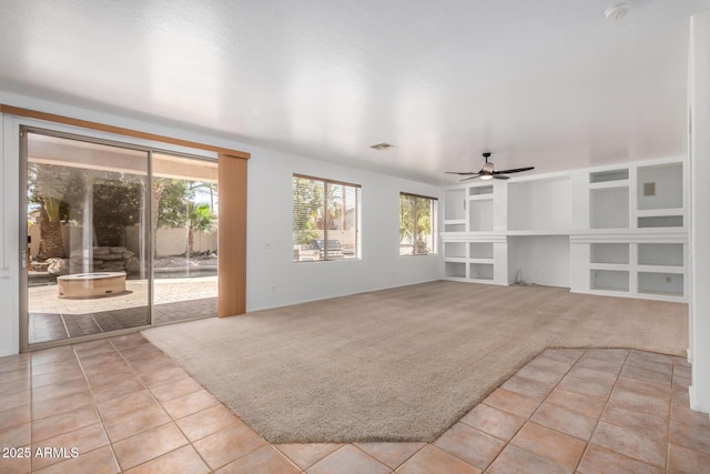 13599 W Monte Vista Rd, Goodyear, AZ 85395 - unfurnished living room featuring light carpet, a ceiling fan, light tile patterned floors, and built in shelves