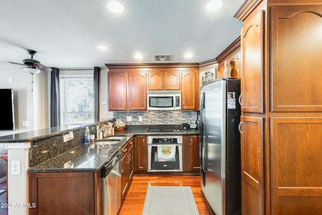 5734 S 21st Pl, Phoenix, AZ 85040 - kitchen with appliances with stainless steel finishes, a peninsula, light wood finished floors, a ceiling fan, and tasteful backsplash