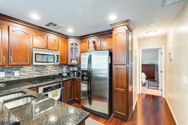 5734 S 21st Pl, Phoenix, AZ 85040 - kitchen with appliances with stainless steel finishes, decorative backsplash, dark wood-style floors, glass insert cabinets, and dark stone countertops