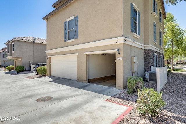 5734 S 21st Pl, Phoenix, AZ 85040 - view of home's exterior featuring a garage, stucco siding, concrete driveway, and stone siding