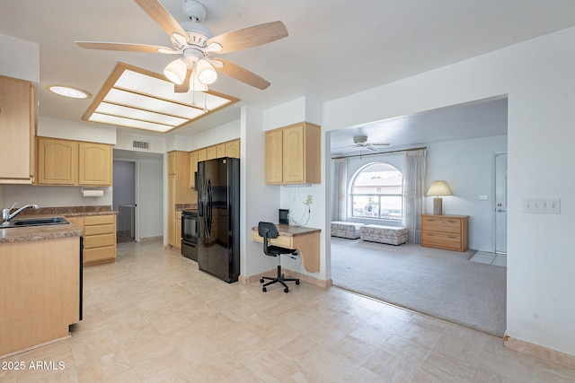 kitchen with visible vents, light carpet, black appliances, light brown cabinets, and a sink