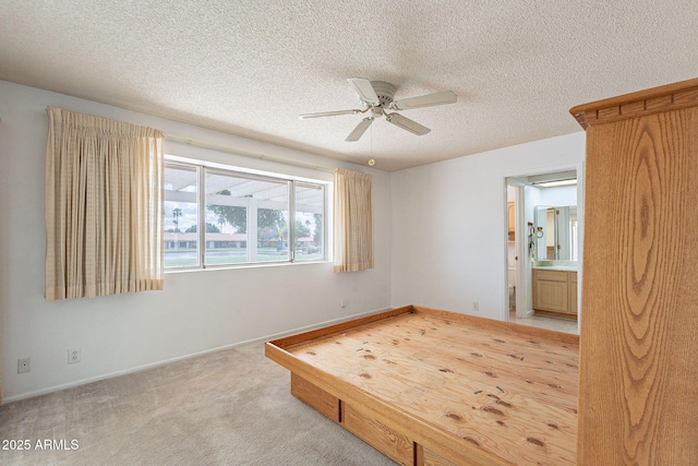 unfurnished bedroom with connected bathroom, baseboards, ceiling fan, light carpet, and a textured ceiling