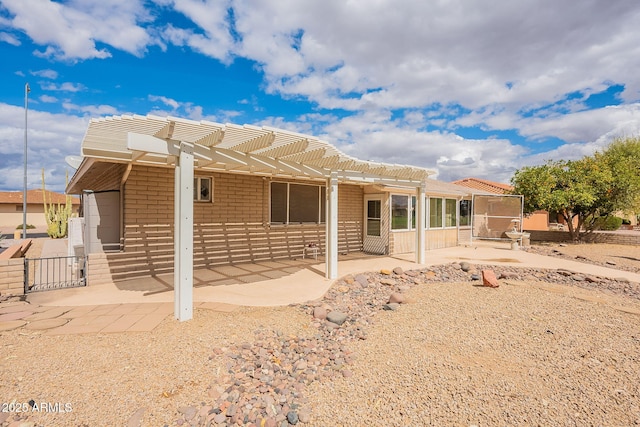 rear view of property with brick siding, a patio area, and a pergola