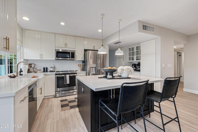 7821 N Via De La Sombre, Scottsdale, AZ 85258 - kitchen with stainless steel appliances, a sink, a kitchen bar, light wood finished floors, and backsplash