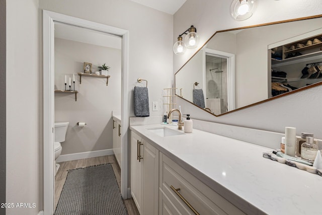7821 N Via De La Sombre, Scottsdale, AZ 85258 - full bathroom with toilet, wood finished floors, vanity, a shower, and baseboards
