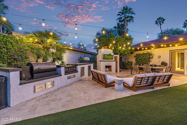 7821 N Via De La Sombre, Scottsdale, AZ 85258 - view of patio with a lit fireplace, exterior kitchen, and grilling area