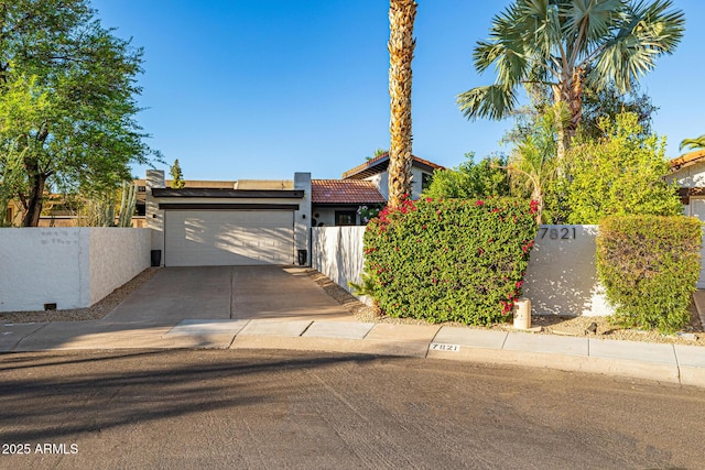 7821 N Via De La Sombre, Scottsdale, AZ 85258 - view of front of home featuring an attached garage, fence, driveway, stucco siding, and a tiled roof