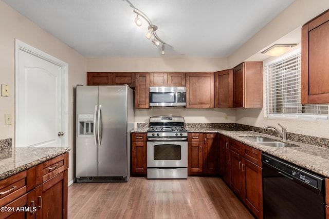 kitchen featuring light stone countertops, sink, appliances with stainless steel finishes, and light hardwood / wood-style flooring