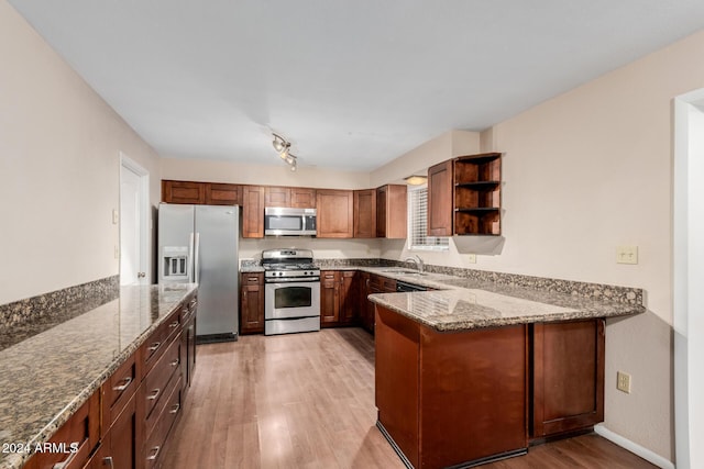 kitchen featuring kitchen peninsula, stone counters, light hardwood / wood-style flooring, and stainless steel appliances