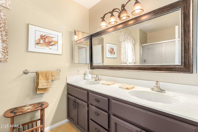 bathroom with baseboards, double vanity, a sink, and a shower stall