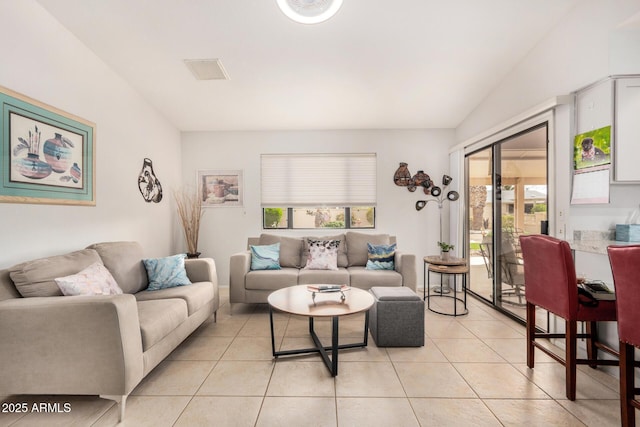 living room with visible vents, vaulted ceiling, and light tile patterned flooring