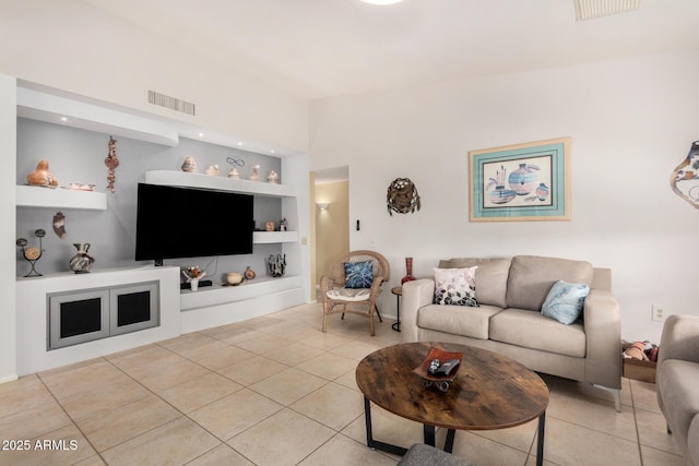 living area with light tile patterned floors, visible vents, and built in features