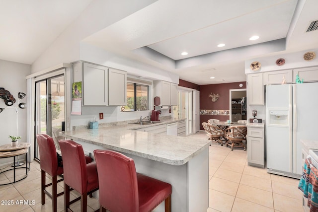 kitchen with white appliances, a tray ceiling, light countertops, and a sink