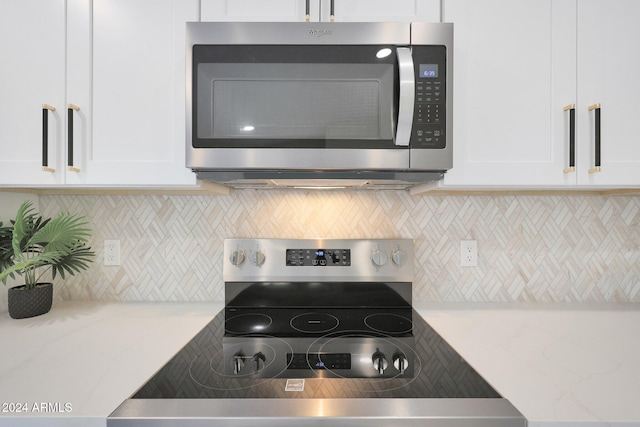 kitchen with black range oven, white cabinetry, and tasteful backsplash