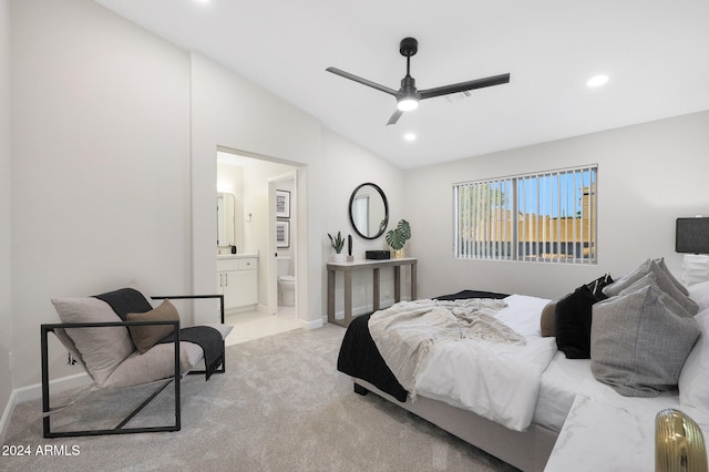 bedroom featuring light carpet, vaulted ceiling, ensuite bath, and ceiling fan