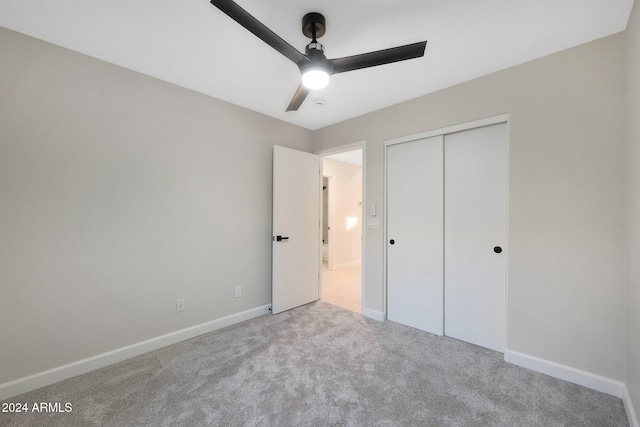 unfurnished bedroom with ceiling fan, light carpet, and a closet