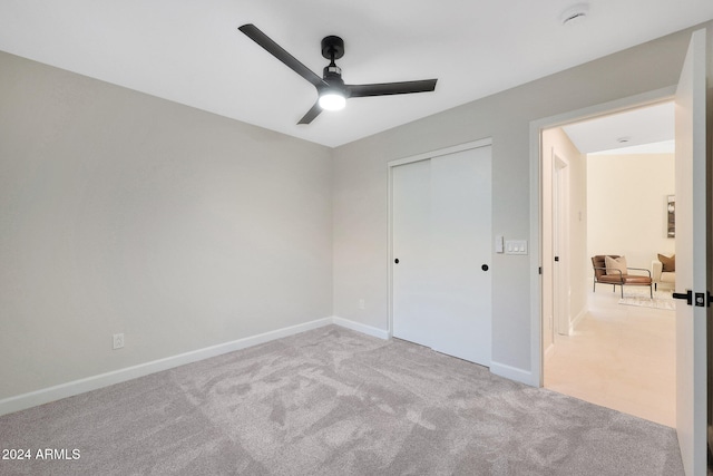 unfurnished bedroom featuring ceiling fan, light colored carpet, and a closet