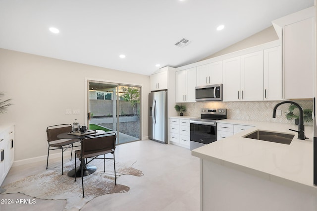 kitchen with stainless steel appliances, white cabinetry, and lofted ceiling