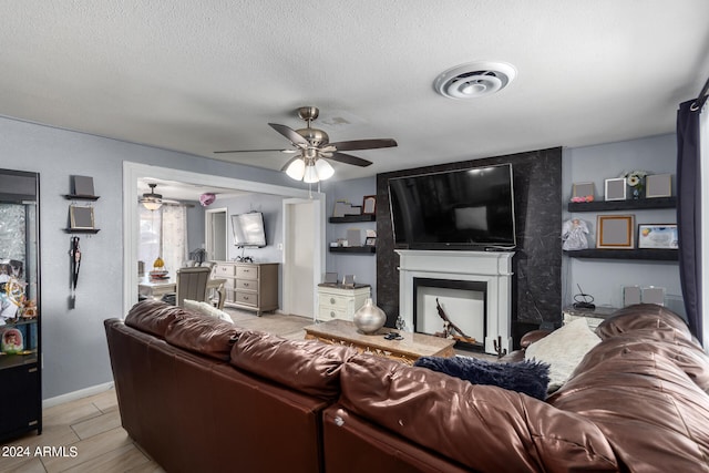 living room featuring a textured ceiling, a fireplace, and ceiling fan