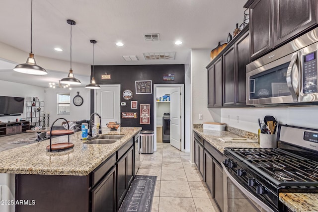 4216 W Harwell Rd, Laveen, AZ 85339 - kitchen featuring appliances with stainless steel finishes, a sink, dark brown cabinetry, light stone countertops, and a center island with sink