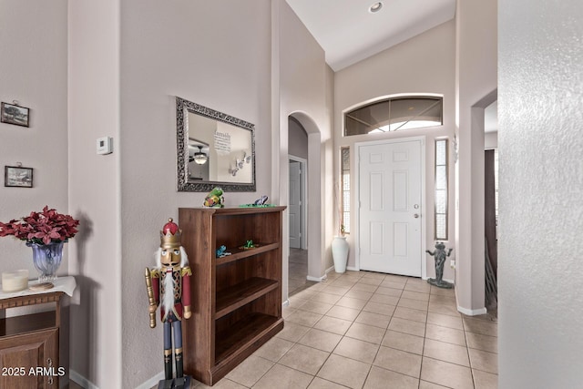 entryway with light tile patterned flooring and high vaulted ceiling