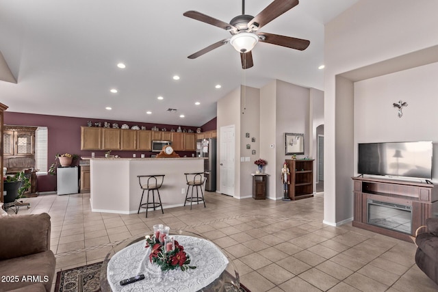 tiled living room featuring ceiling fan and high vaulted ceiling