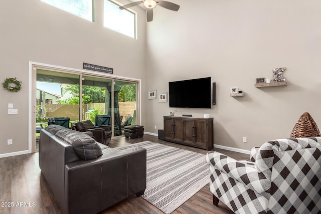 living room featuring ceiling fan, a towering ceiling, and dark hardwood / wood-style floors