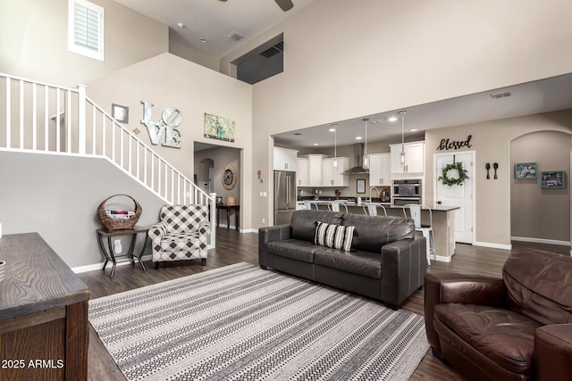 living room with a high ceiling, ceiling fan, sink, and dark hardwood / wood-style floors