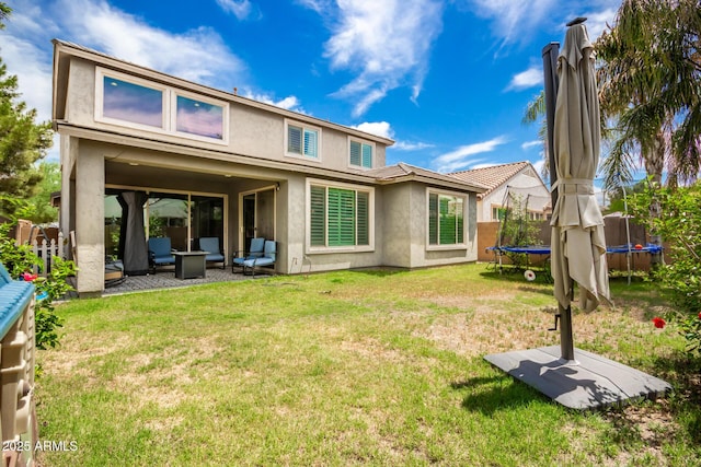 rear view of property with a lawn, a patio area, and a trampoline